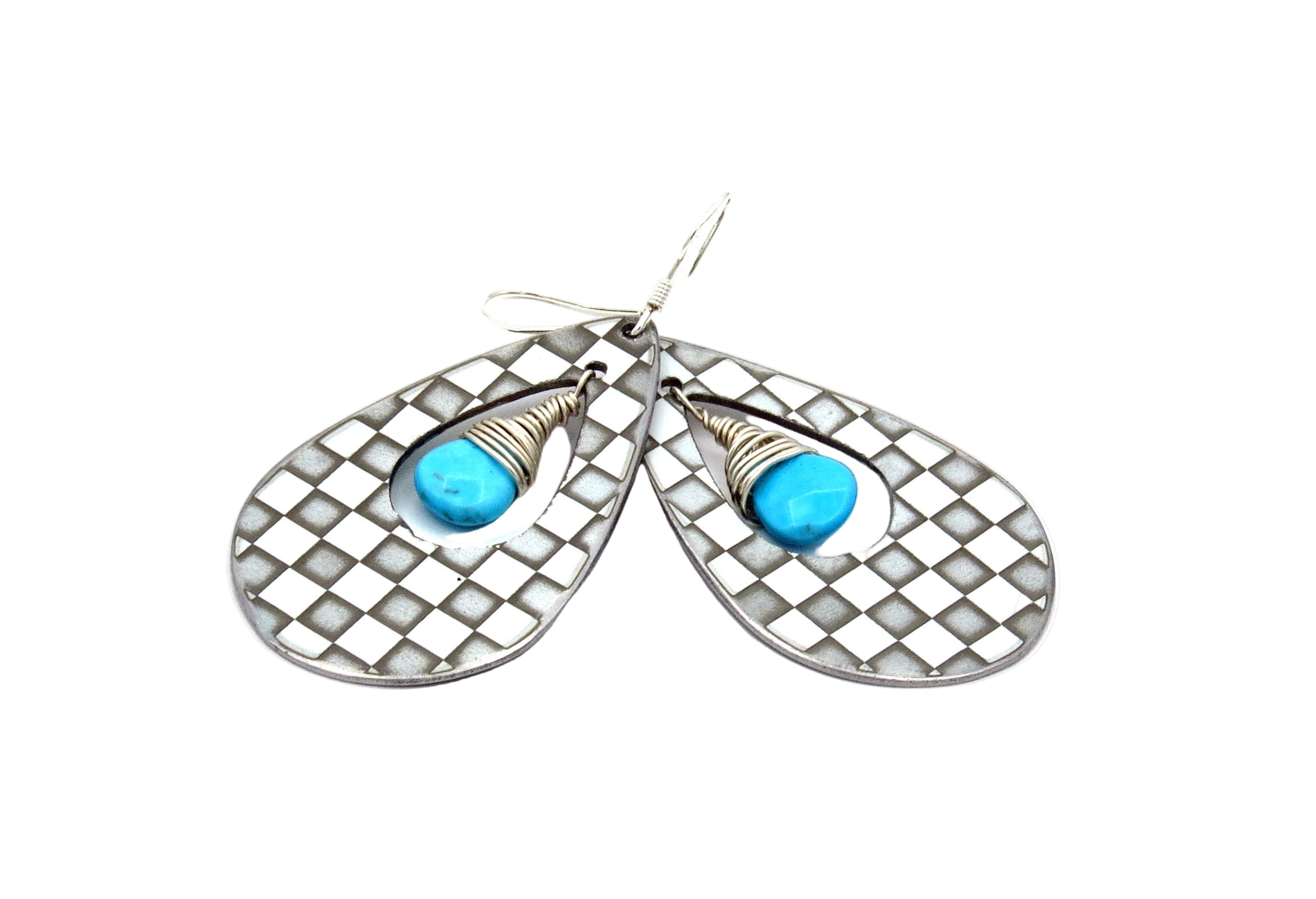 Pair of earrings with checkered design and turquoise stones on a white background