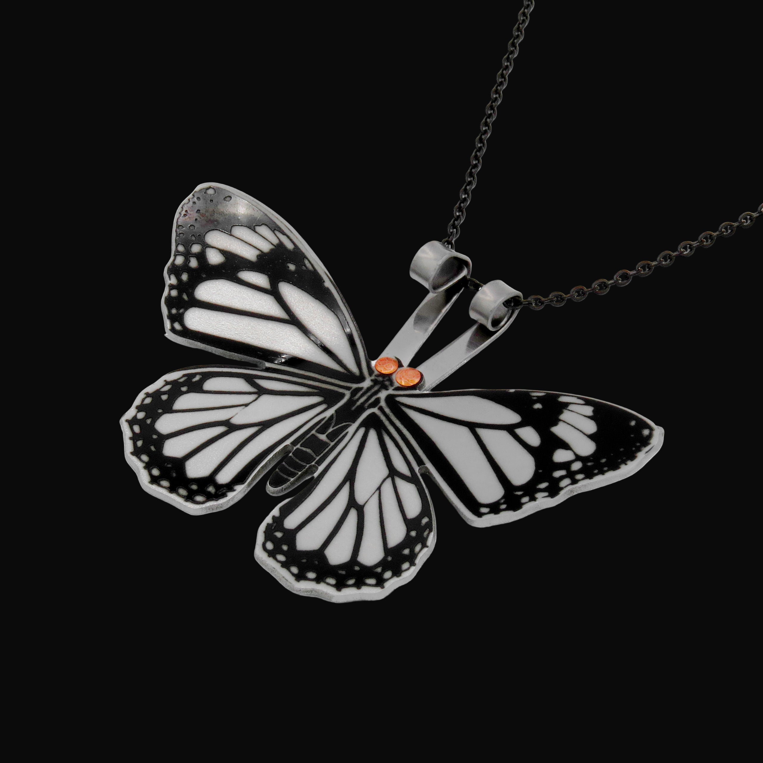 Butterfly-shaped pendant on a chain against a black background