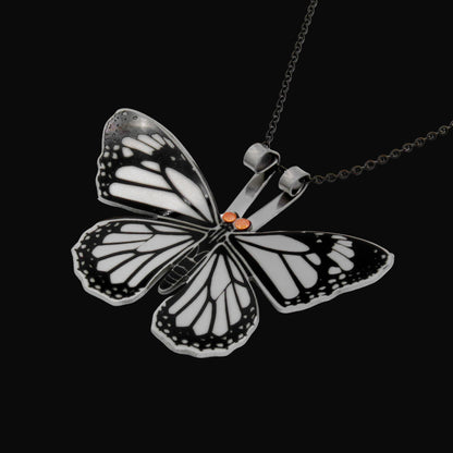 Butterfly-shaped pendant on a chain against a black background