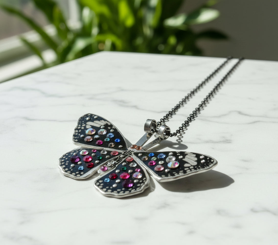 Butterfly-shaped pendant with colorful gemstones on a gray background