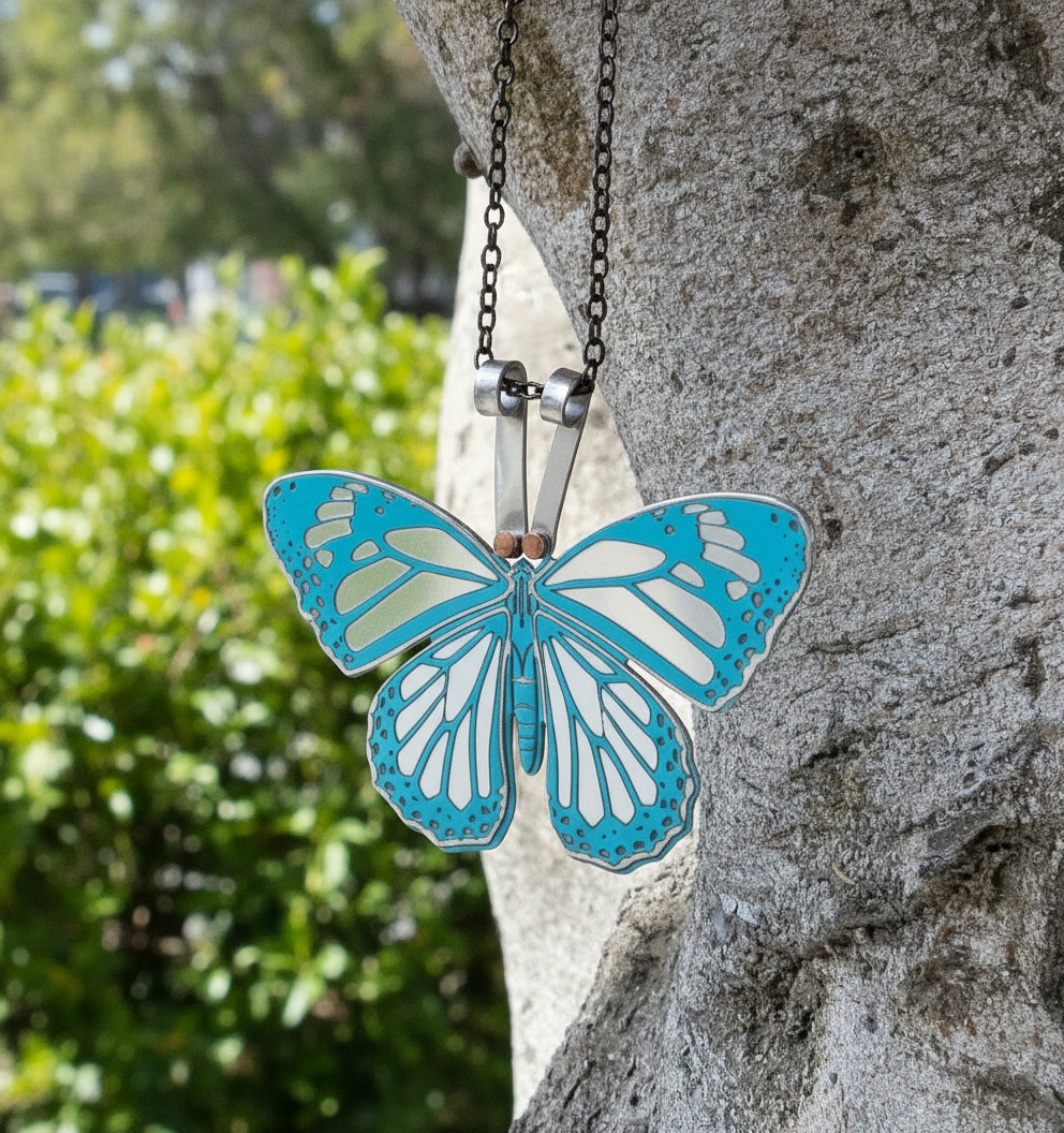 Butterfly-shaped pendant on a chain against a stone background