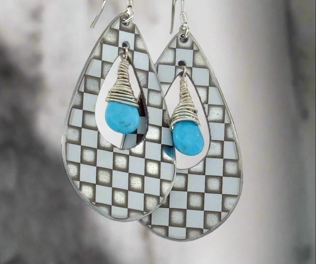 Teardrop-shaped earrings with turquoise stones and checkered pattern on a blurred background