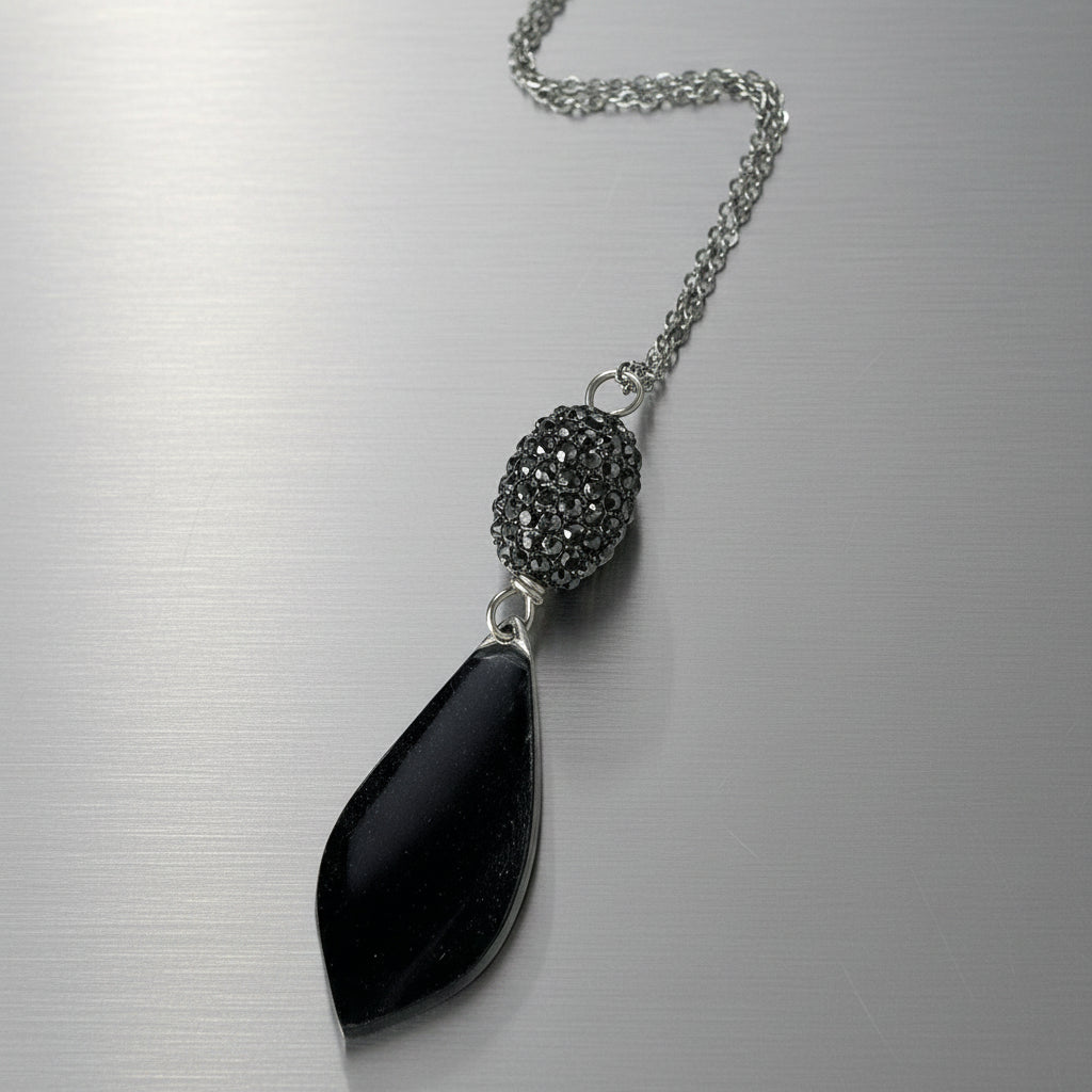 Necklace with a black pendant and textured bead on a light gray background