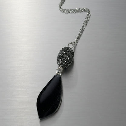 Necklace with a black pendant and textured bead on a light gray background