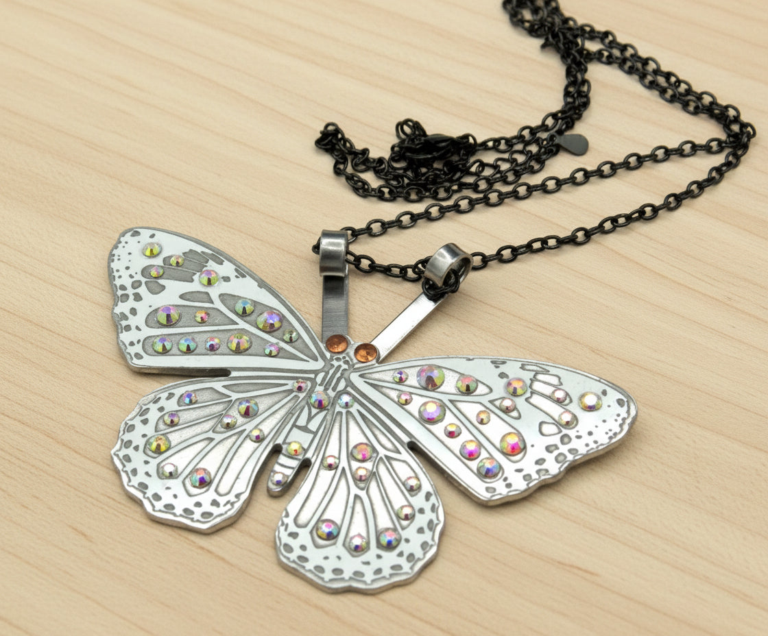 Butterfly-shaped pendant with colorful stones on a black chain against a white background